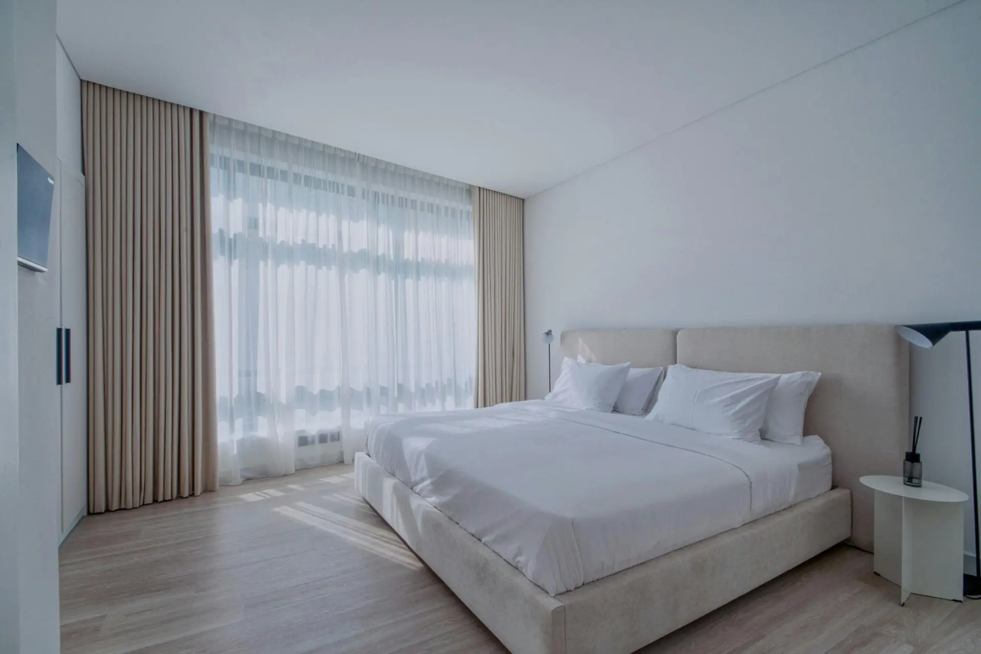A serene and modern bedroom interior with elegant neutral tones and natural light.